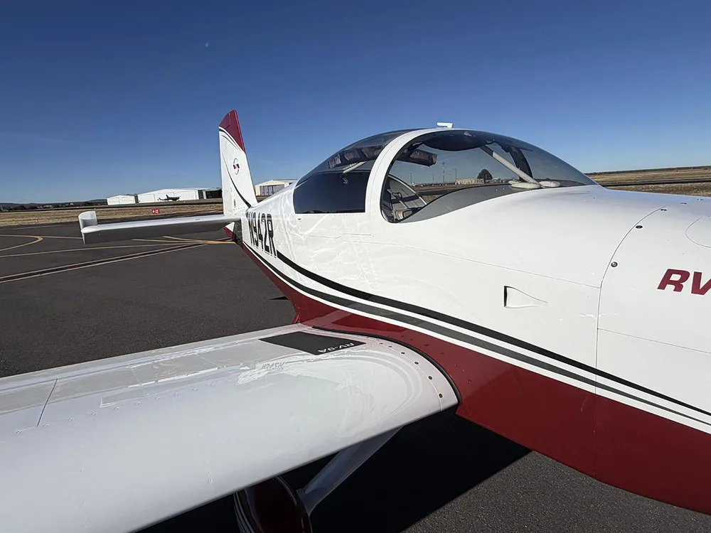 A close-up side view of the cockpit and wing of the white and red Van's RV-9A aircraft N942R.