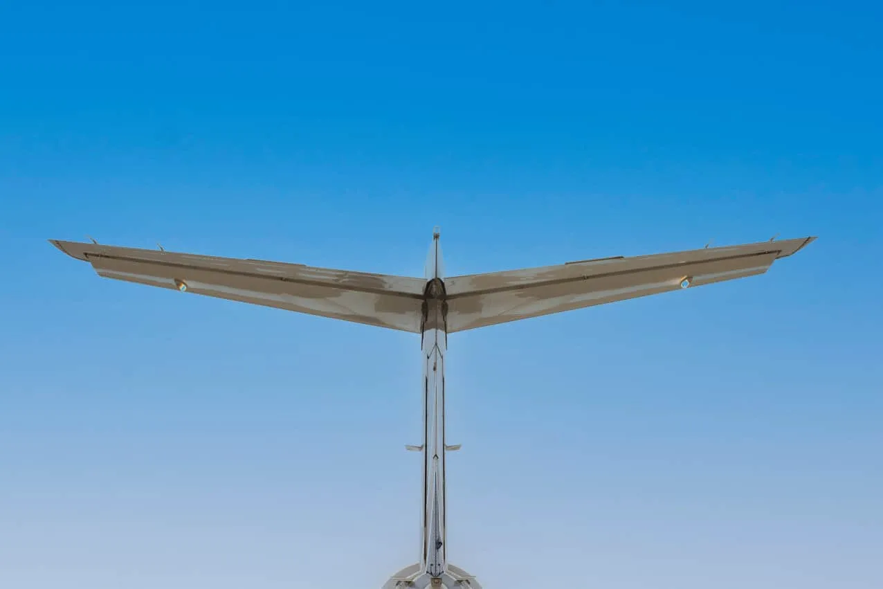 A rear view of the private jet's T-tail and horizontal stabilizer against a clear blue sky.