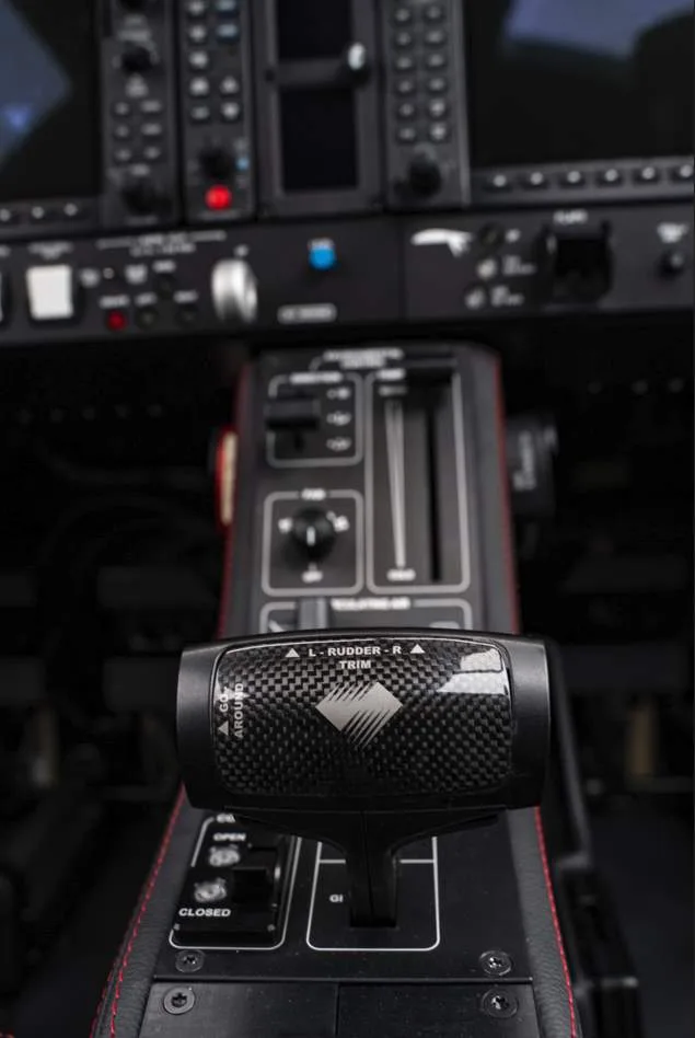 A close-up view of an aircraft's throttle quadrant with a carbon fiber trim control, showing "L RUDDER R TRIM" label.