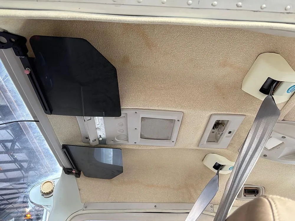 The beige ceiling of a small aircraft cabin with sun visors and overhead lights.