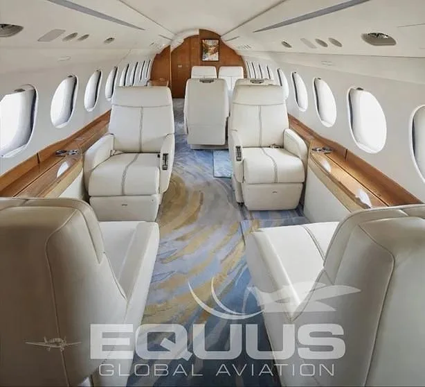 The luxurious interior of a private jet cabin features cream leather seats and a patterned carpet.