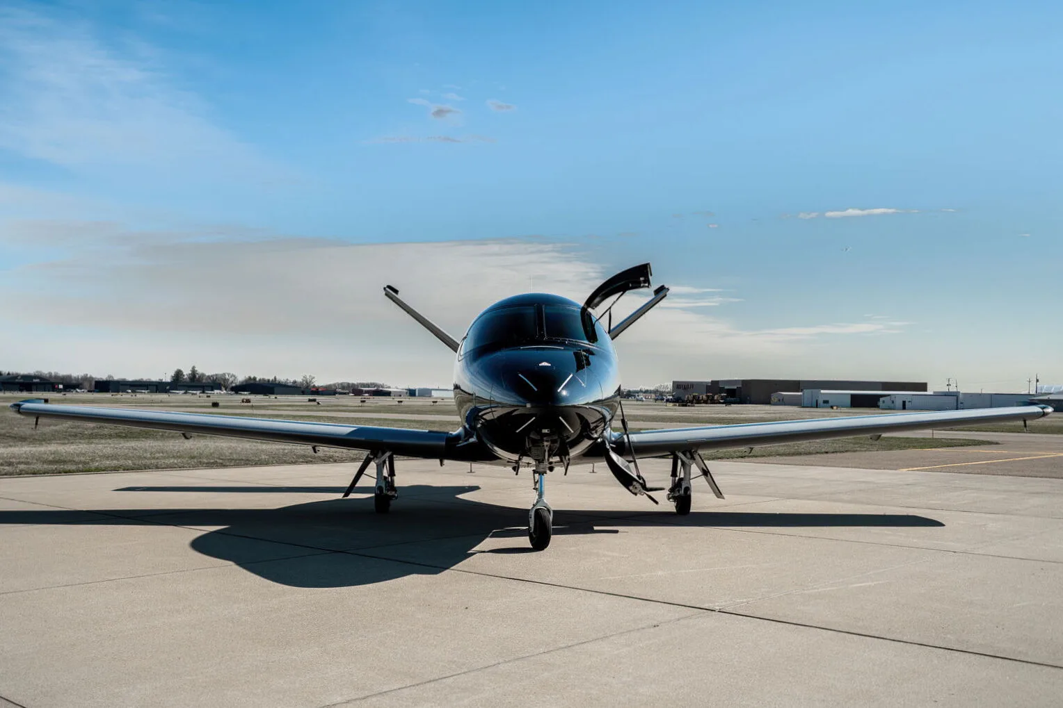 Front view of a black Cirrus Vision Jet (N71AB) parked on an airport tarmac with its main door open.