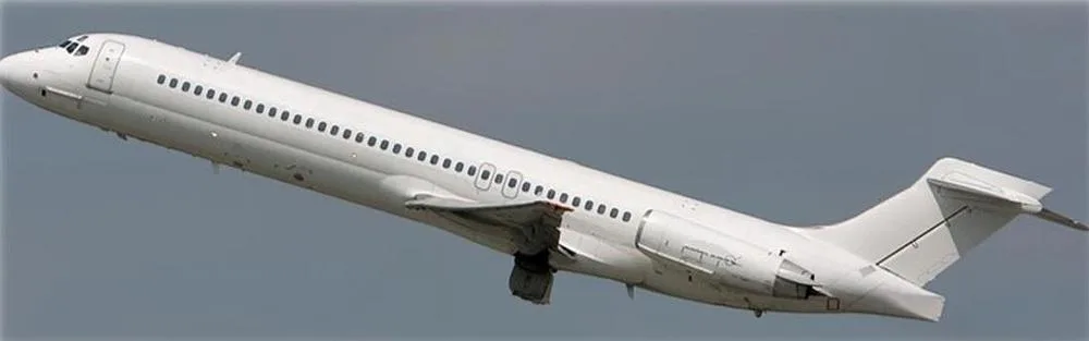 A white McDonnell Douglas MD-80 series aircraft takes off against a grey sky.