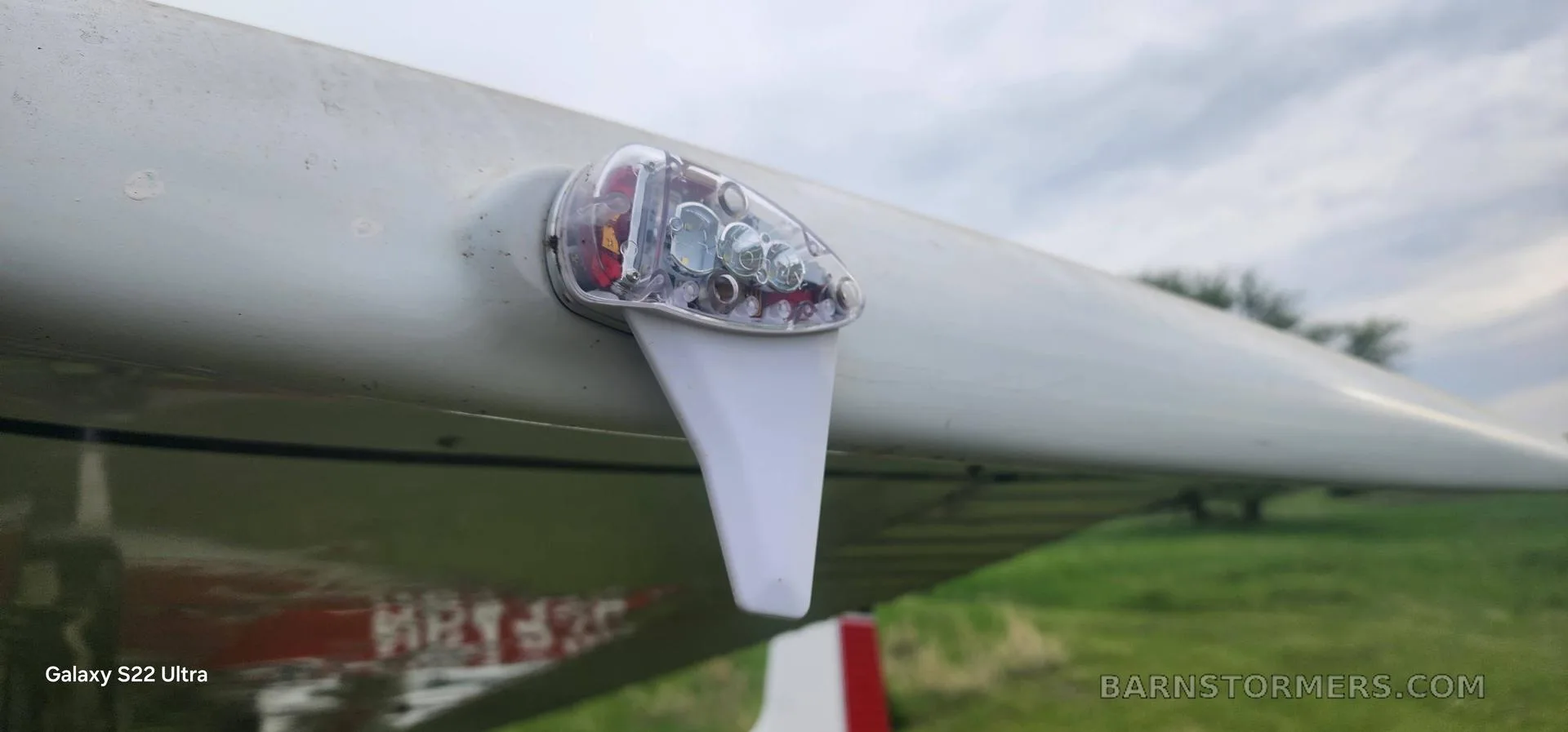 A close-up view of a clear wingtip navigation light on a white aircraft wing.