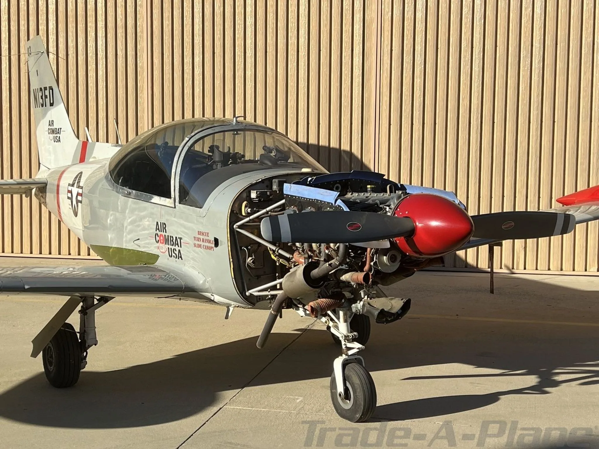 The N13FD aircraft is parked on the tarmac with its engine cowling removed, revealing the engine components.