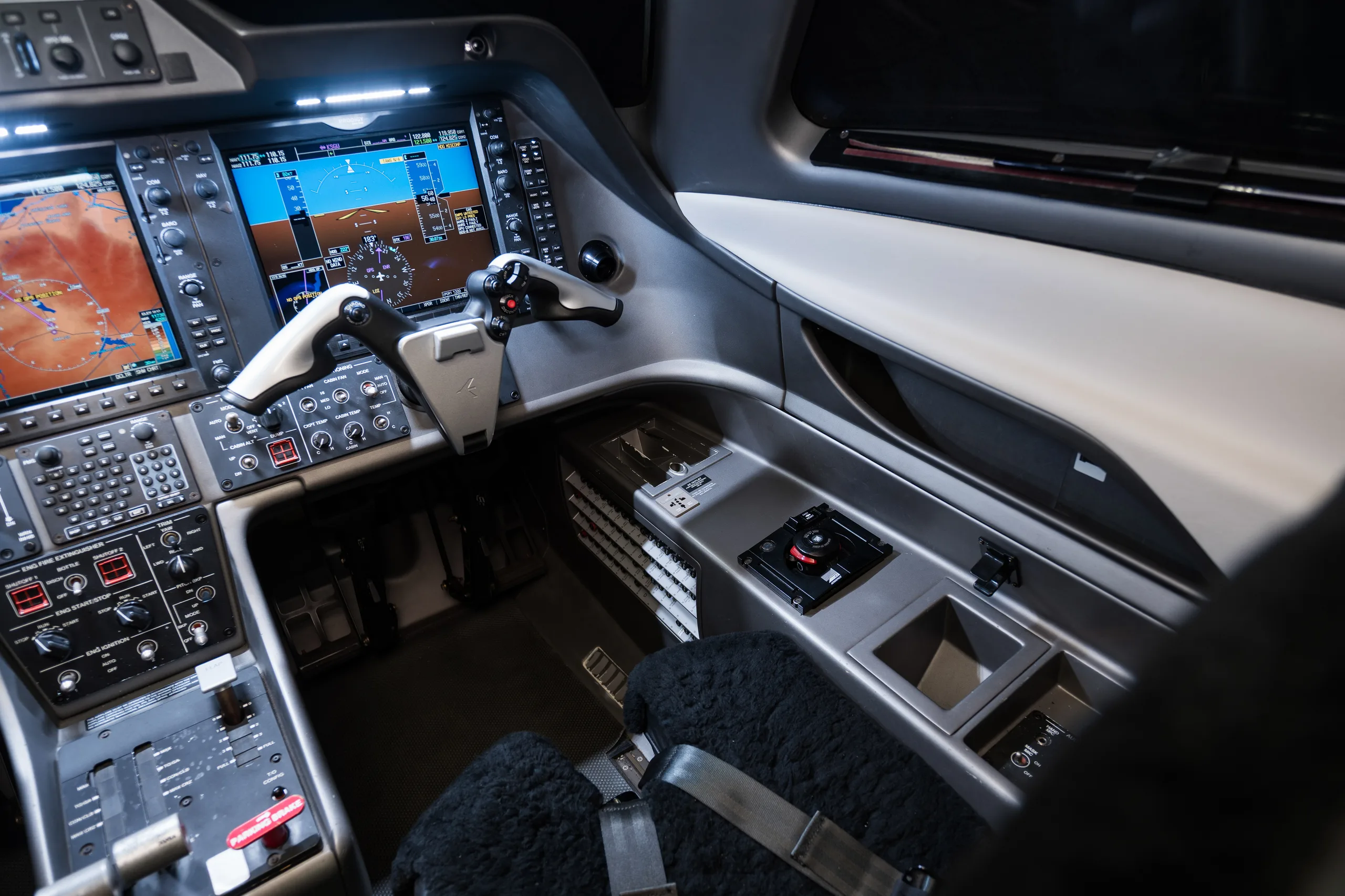 An overhead view of the cockpit of an Embraer Phenom 100, showing the instrument panel, yokes, and center console.