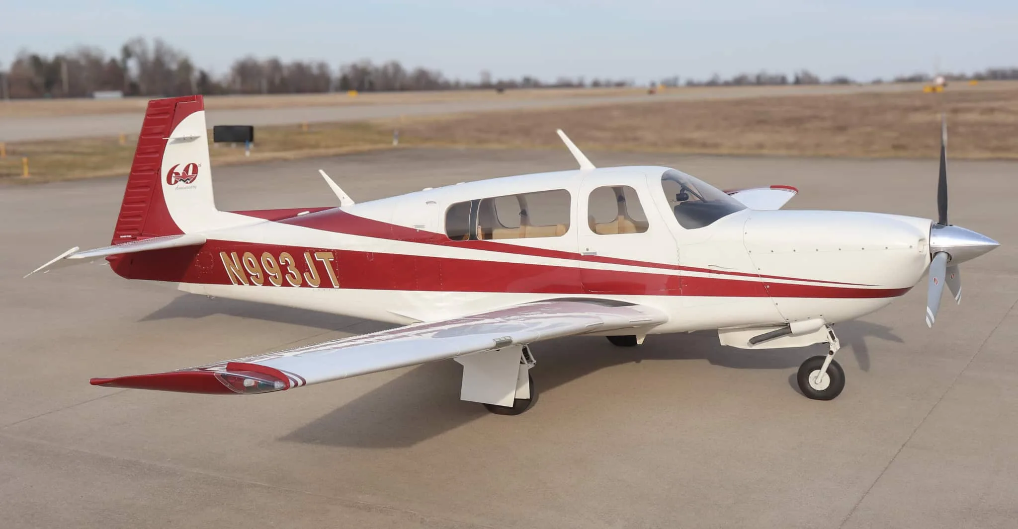 A white and red single-engine propeller aircraft, N993JT, parked on an airfield.