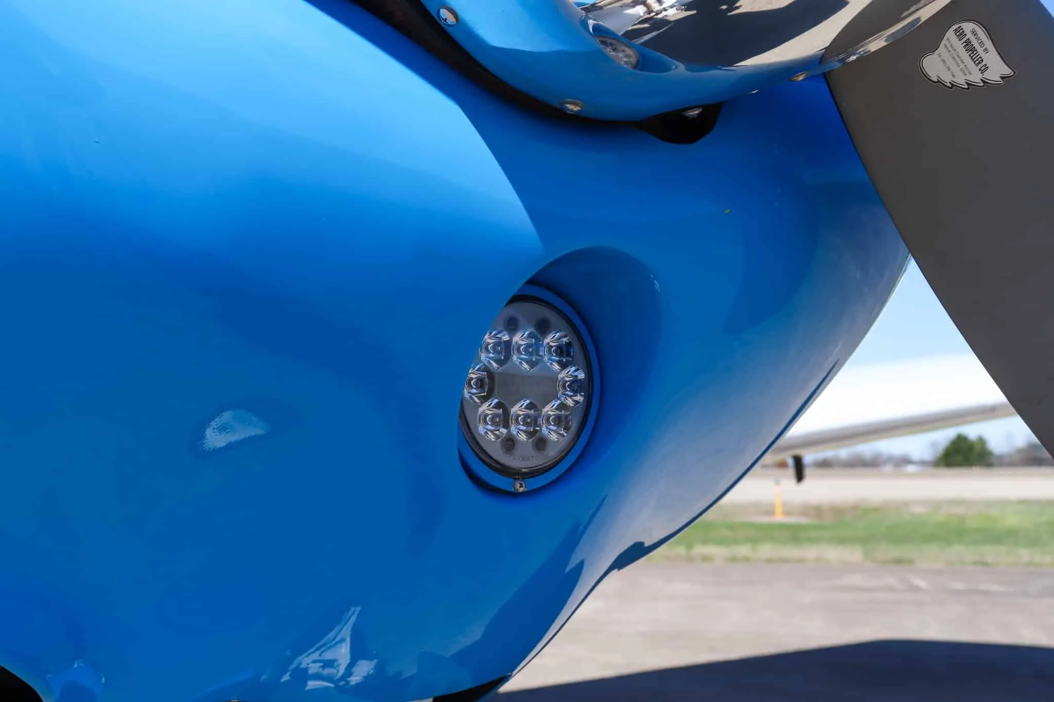 A close-up view of the LED landing light on the blue nose of the Piper Cherokee aircraft.