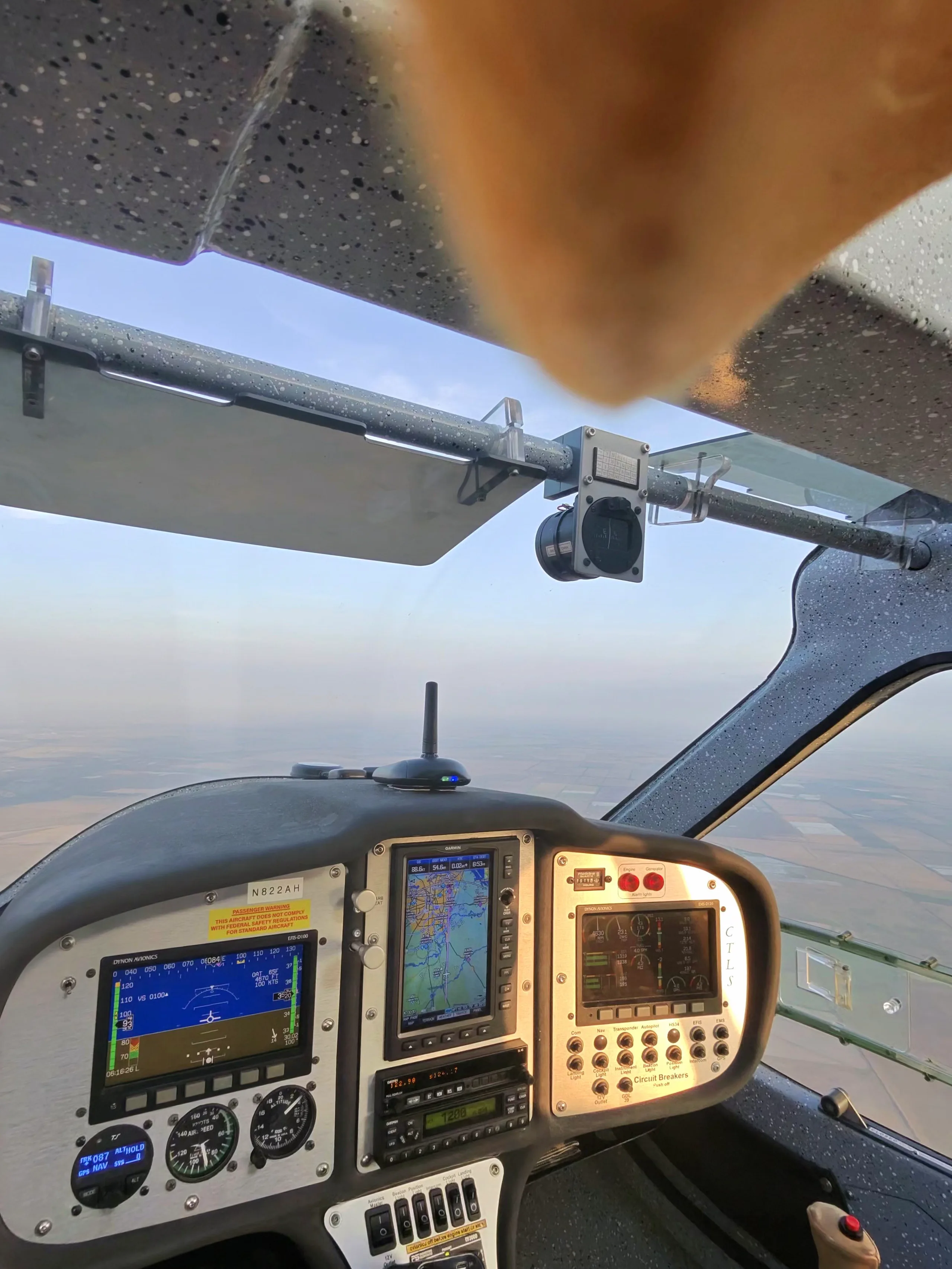 The cockpit of a Flight Design CTLS aircraft in flight, showing the instrument panel with digital displays and a view of the ground below.