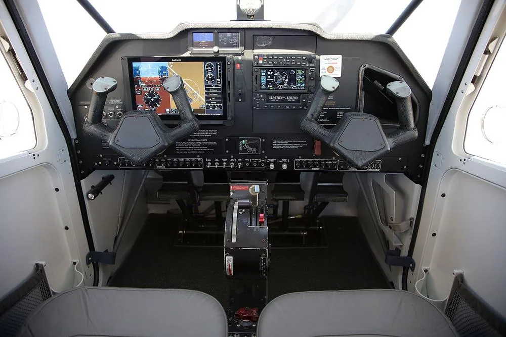 The cockpit of an aircraft featuring dual yokes, modern glass displays, and traditional instruments.