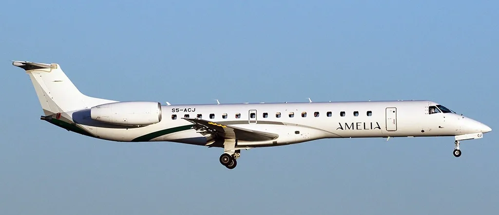 A white Embraer ERJ-145 regional jet with green accents and "AMELIA" livery is shown in flight against a clear blue sky.