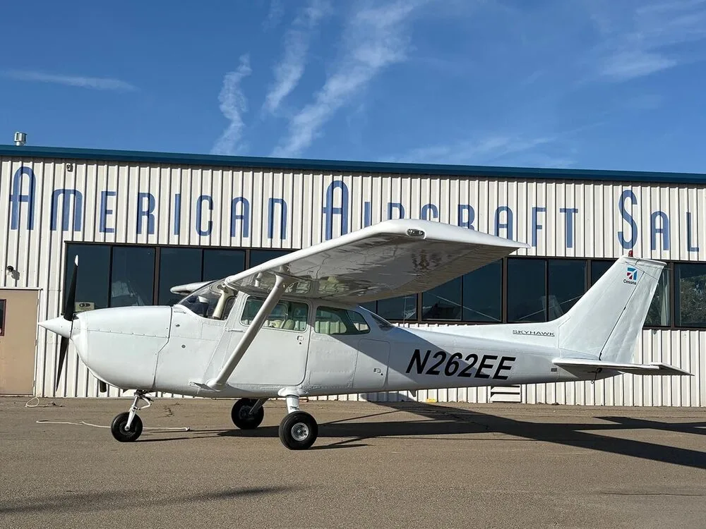 A side view of a white Cessna Skyhawk N262EE parked on an tarmac.