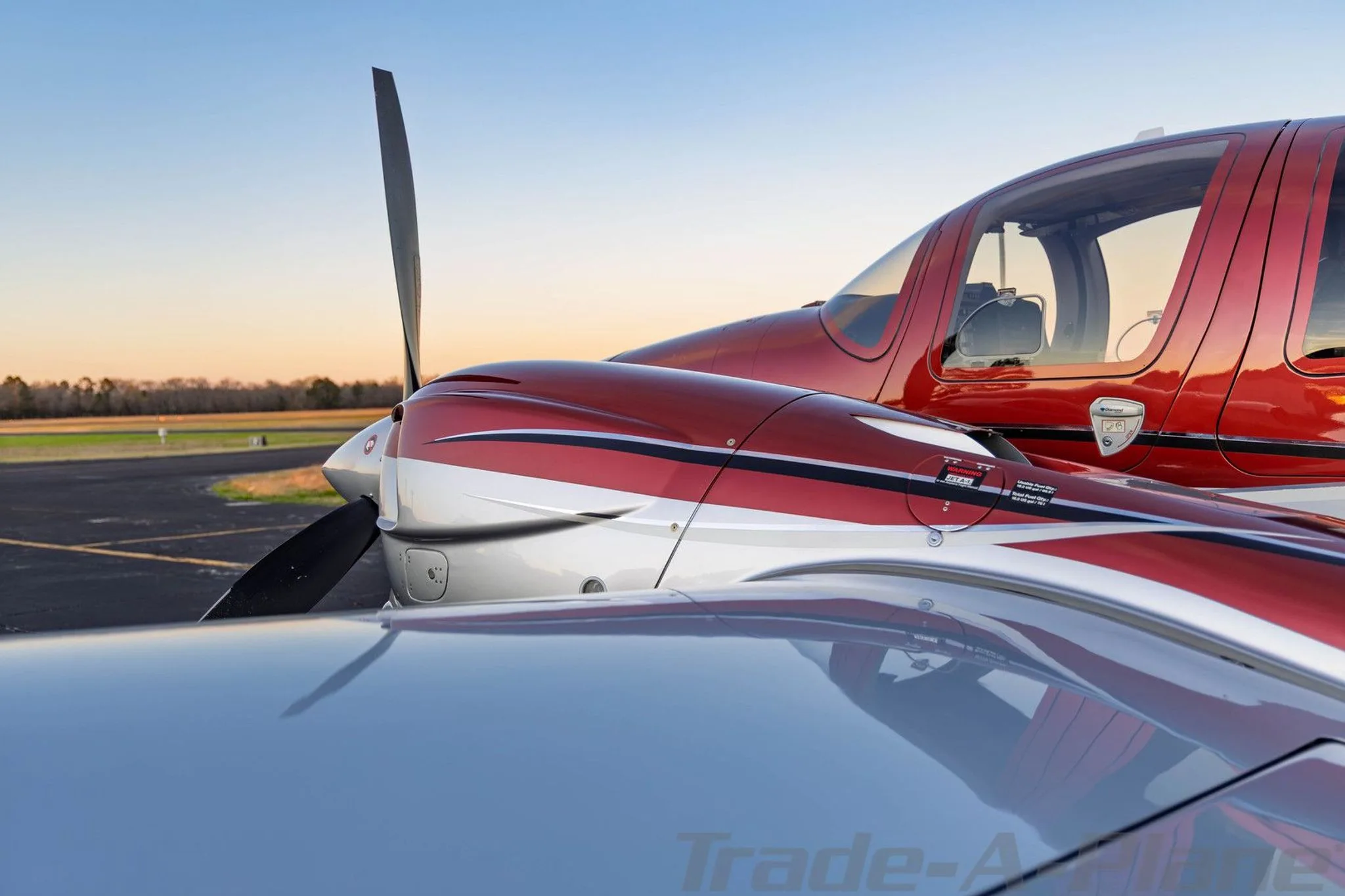 A close-up view of the red and silver engine cowling and fuselage of the Diamond DA62.