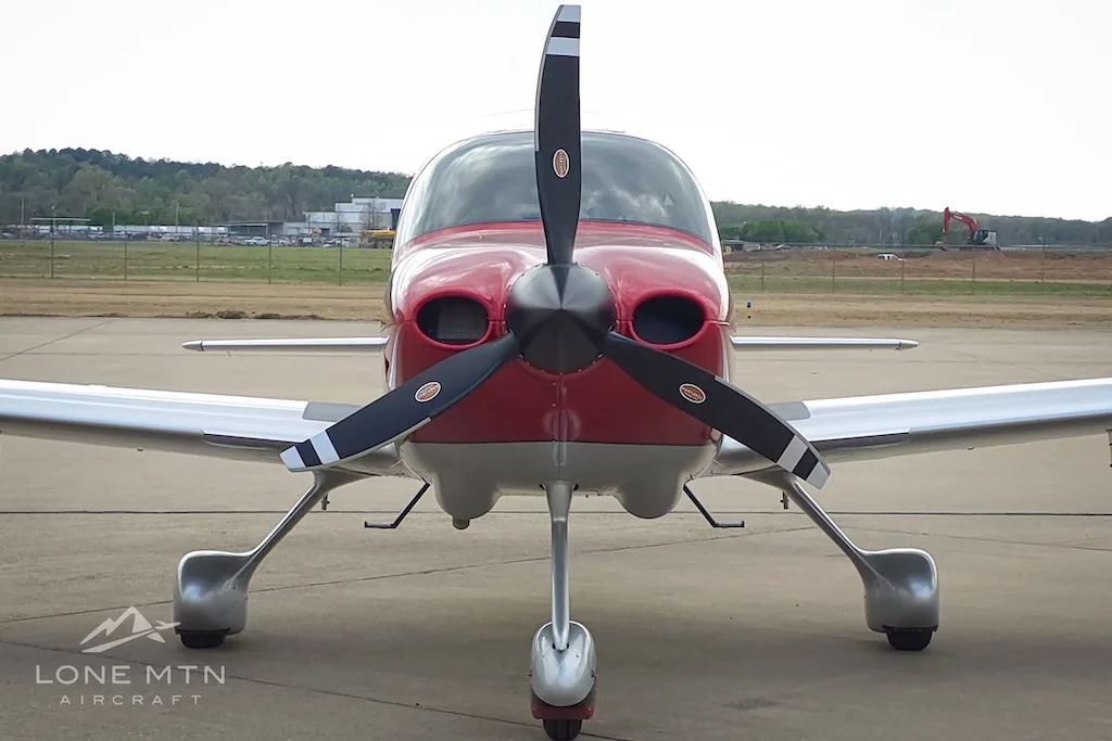 A head-on view of the red and silver Cirrus SR22 aircraft, N6225, showing its propeller and landing gear.