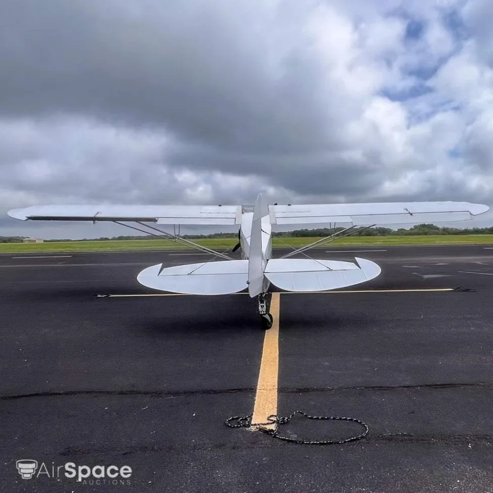 A rear view of the white high-wing aircraft N3984Z with red stripes, parked on an asphalt runway.