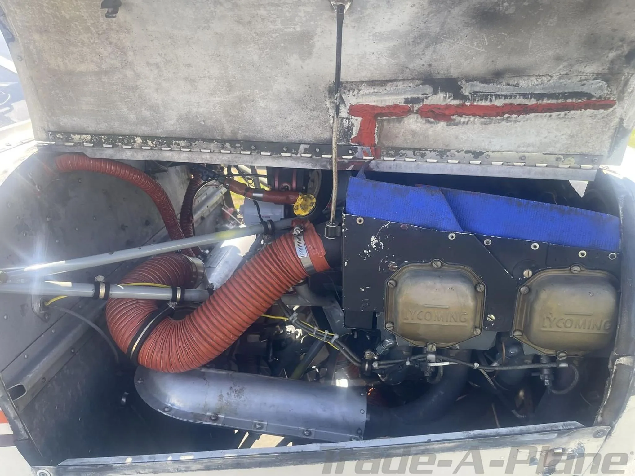 Detailed view of the aircraft's Lycoming engine, showing cylinders, red hoses, and internal components.