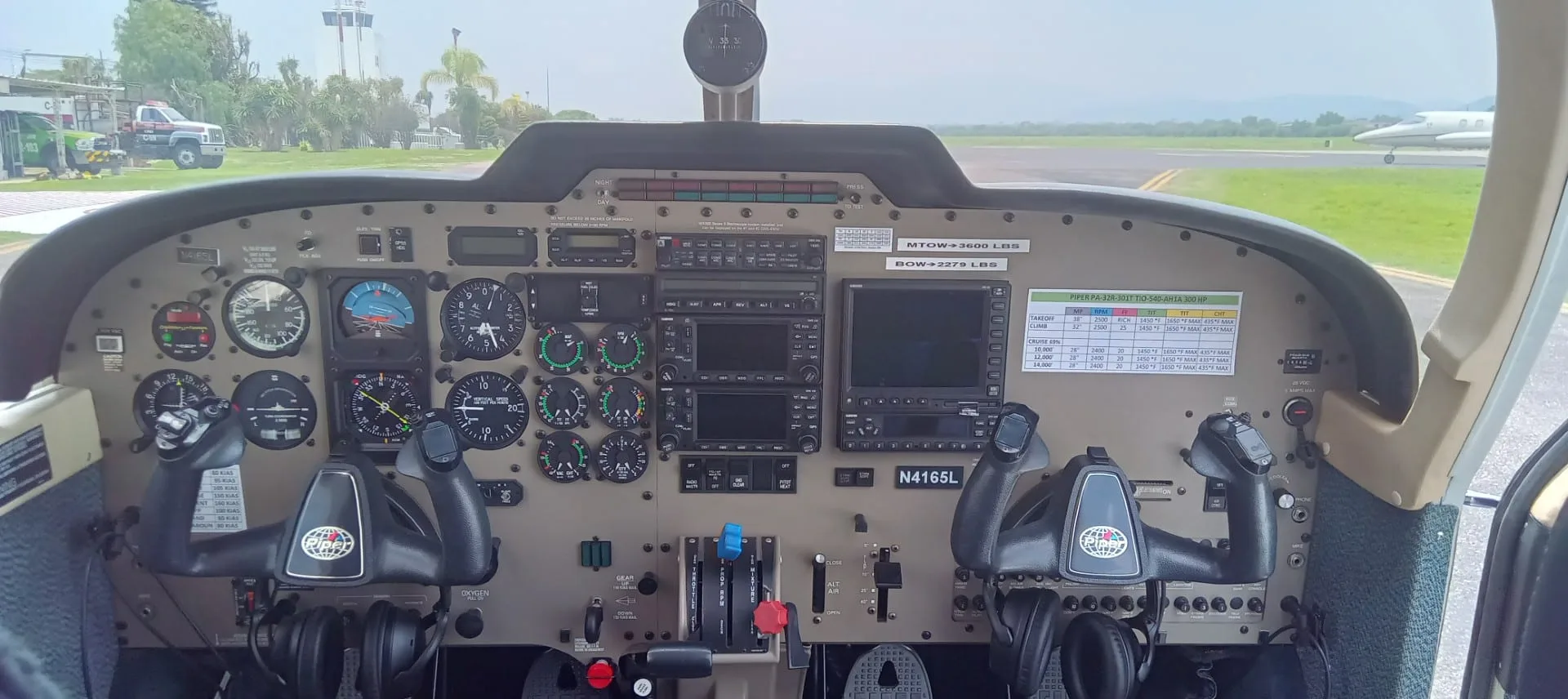 Full view of a small aircraft cockpit instrument panel with dual yokes and various gauges and screens.