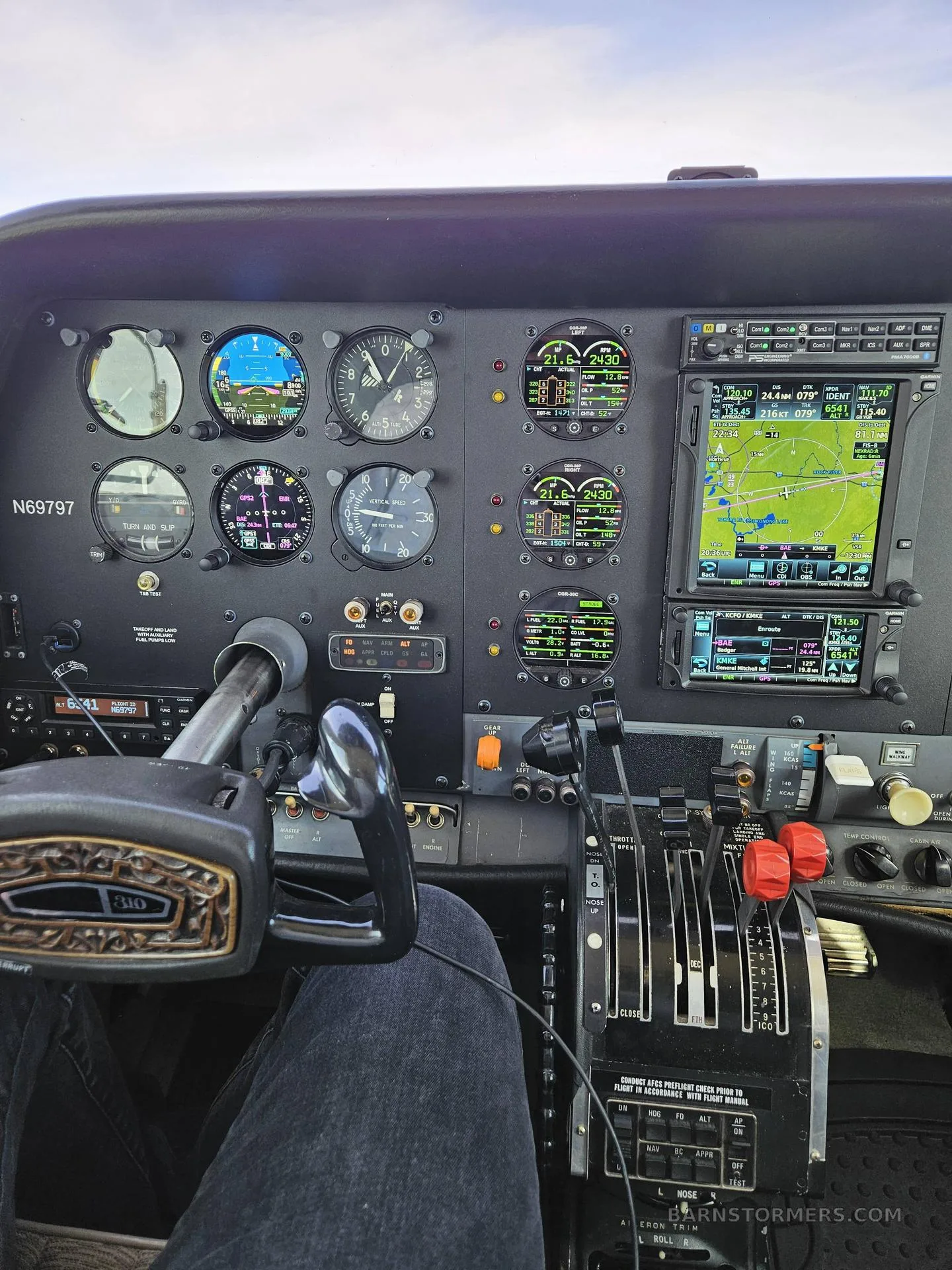 The cockpit of a twin-engine aircraft shows the instrument panel with analog gauges and digital displays, including a GPS map.