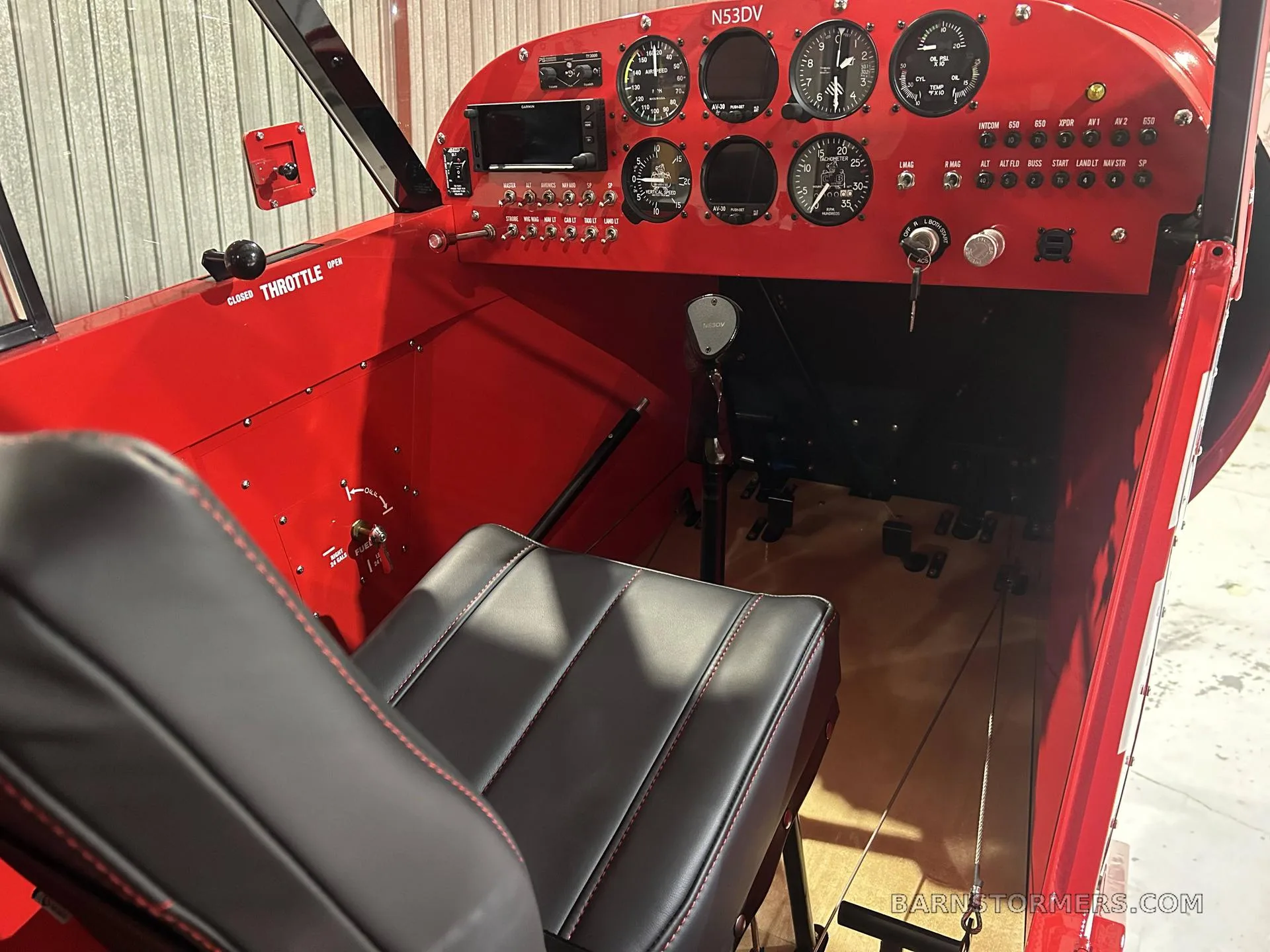 The cockpit of a PA-18 Supercub featuring red interior and instruments.