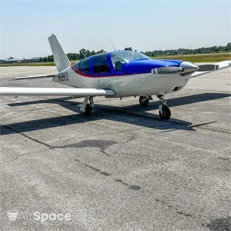 A white and blue single-engine propeller aircraft with registration N68KD on a tarmac under a clear sky.