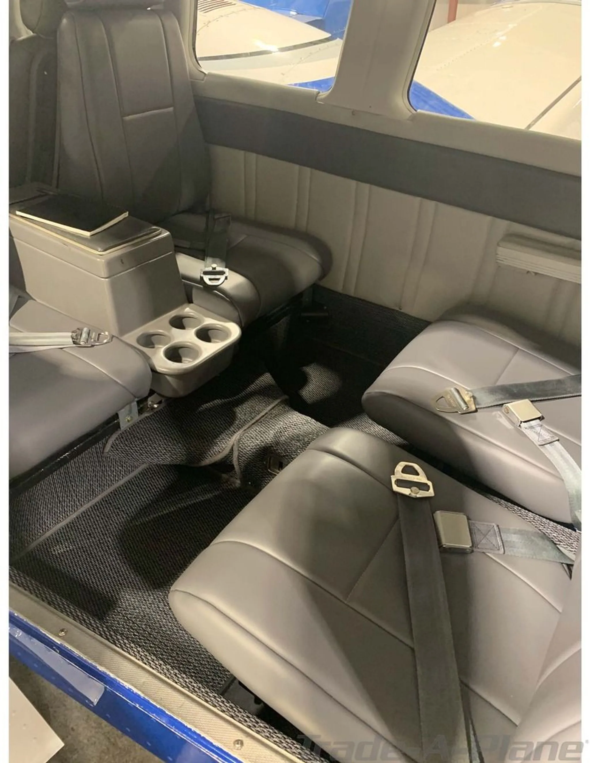 The aircraft's gray interior cabin with four seats and a center console with cup holders.