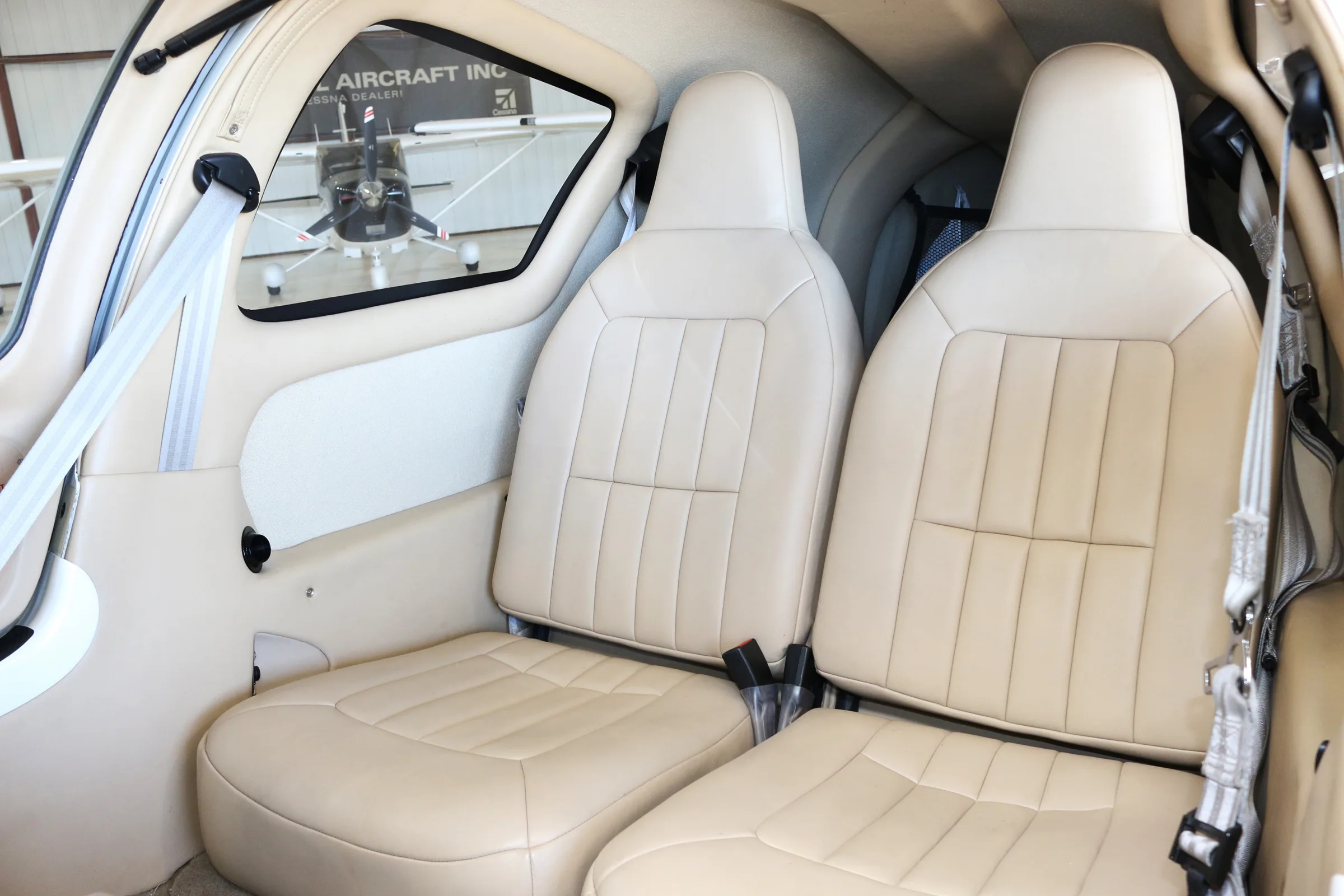 The light beige leather interior cabin seats of a small aircraft are shown.