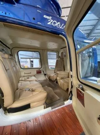 View of the helicopter cabin with beige leather seats and open door.