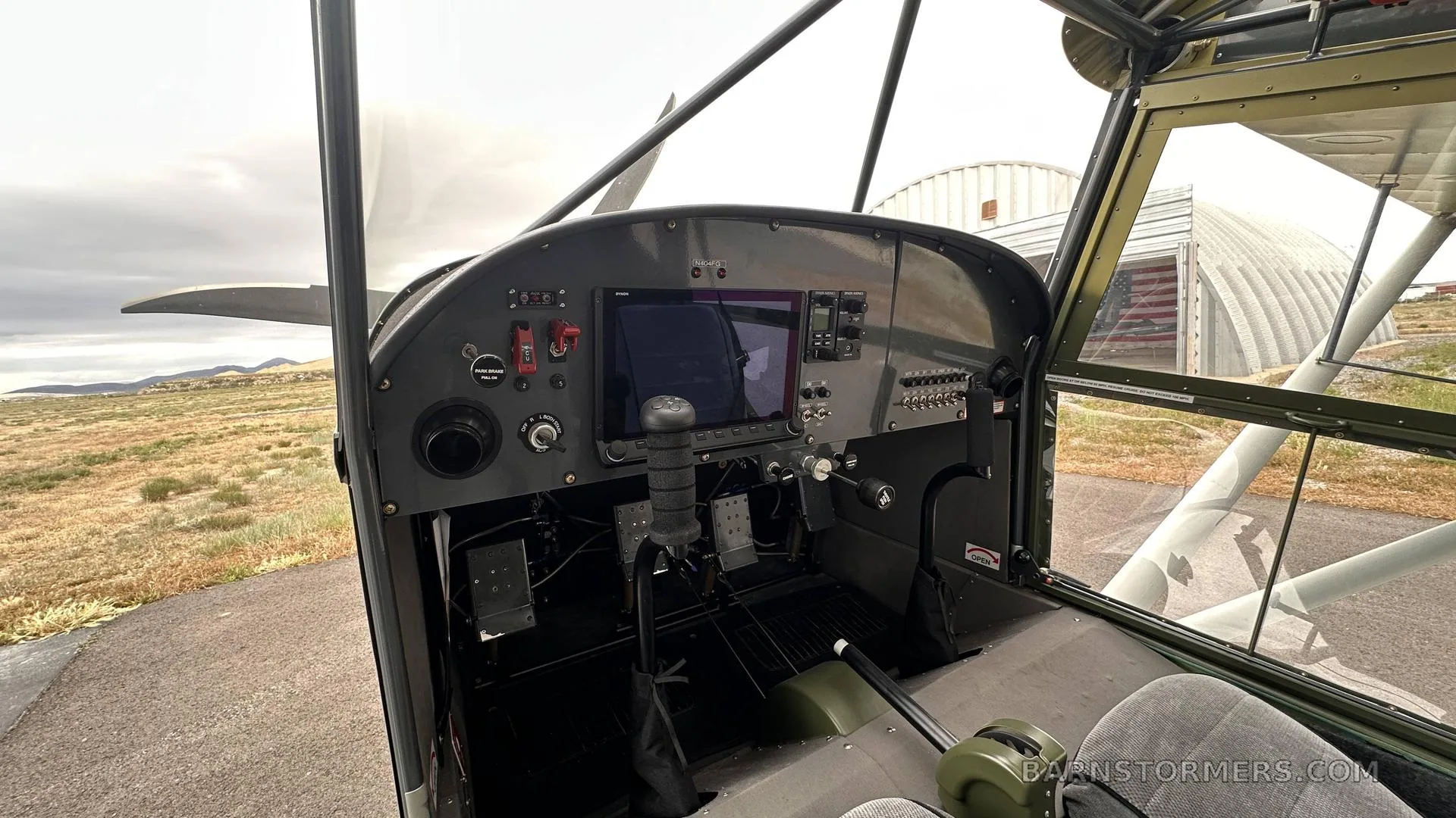 The cockpit of a light aircraft features a modern digital display, control stick, and rudder pedals.