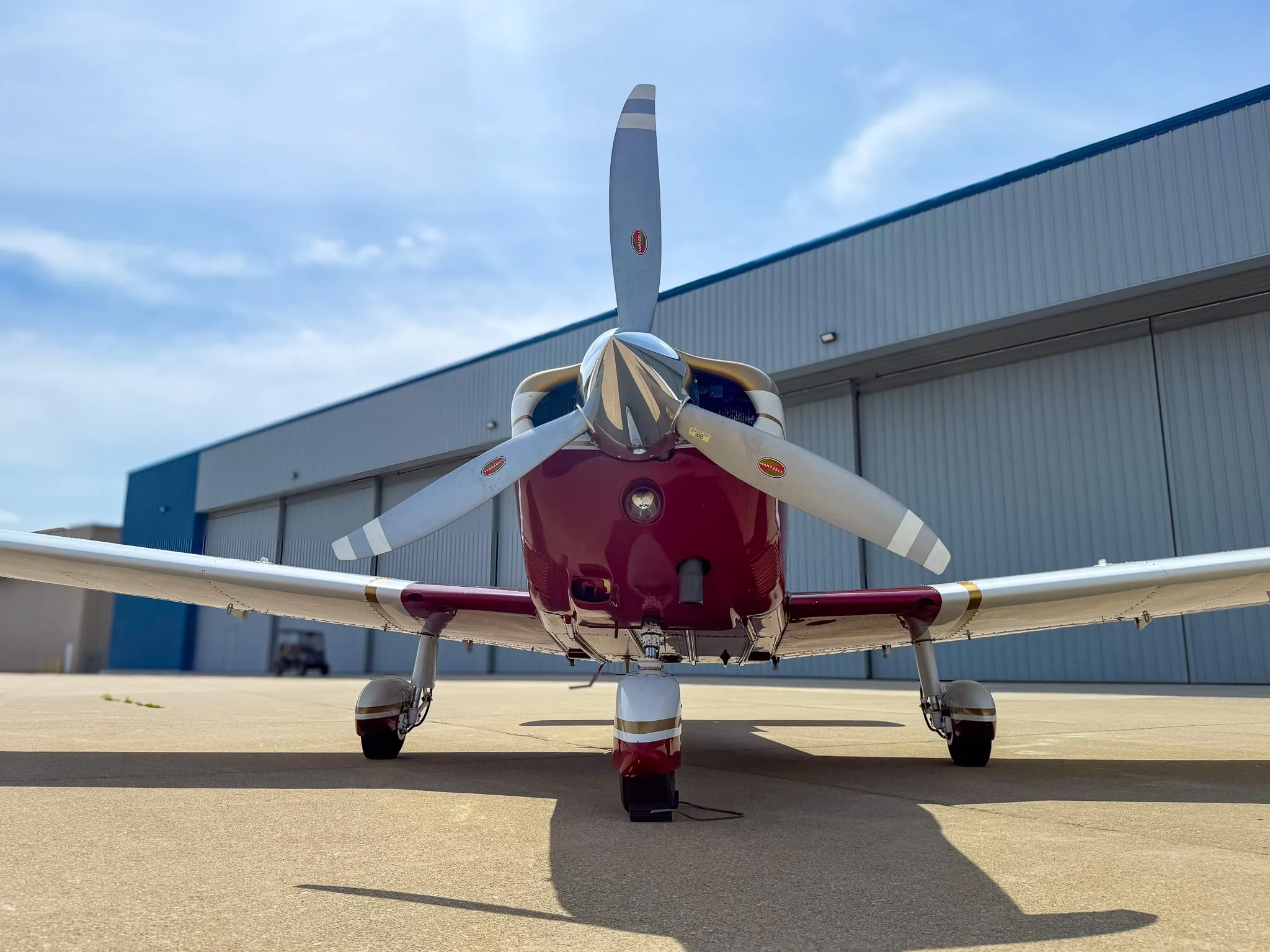A head-on view of the red, white, and gold Piper Cherokee aircraft (N8534N) with its propeller centered.
