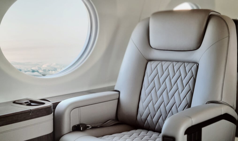 Close-up of a luxurious aircraft seat next to a window.