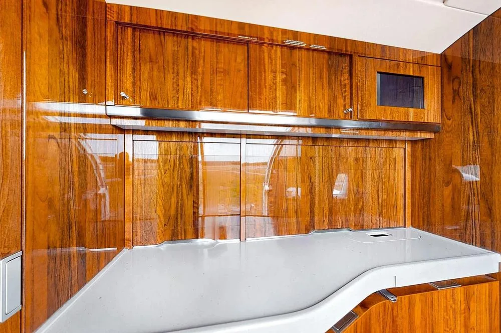 A close-up of the aircraft's galley or cabinet area with glossy wood finishes and a light-colored countertop.