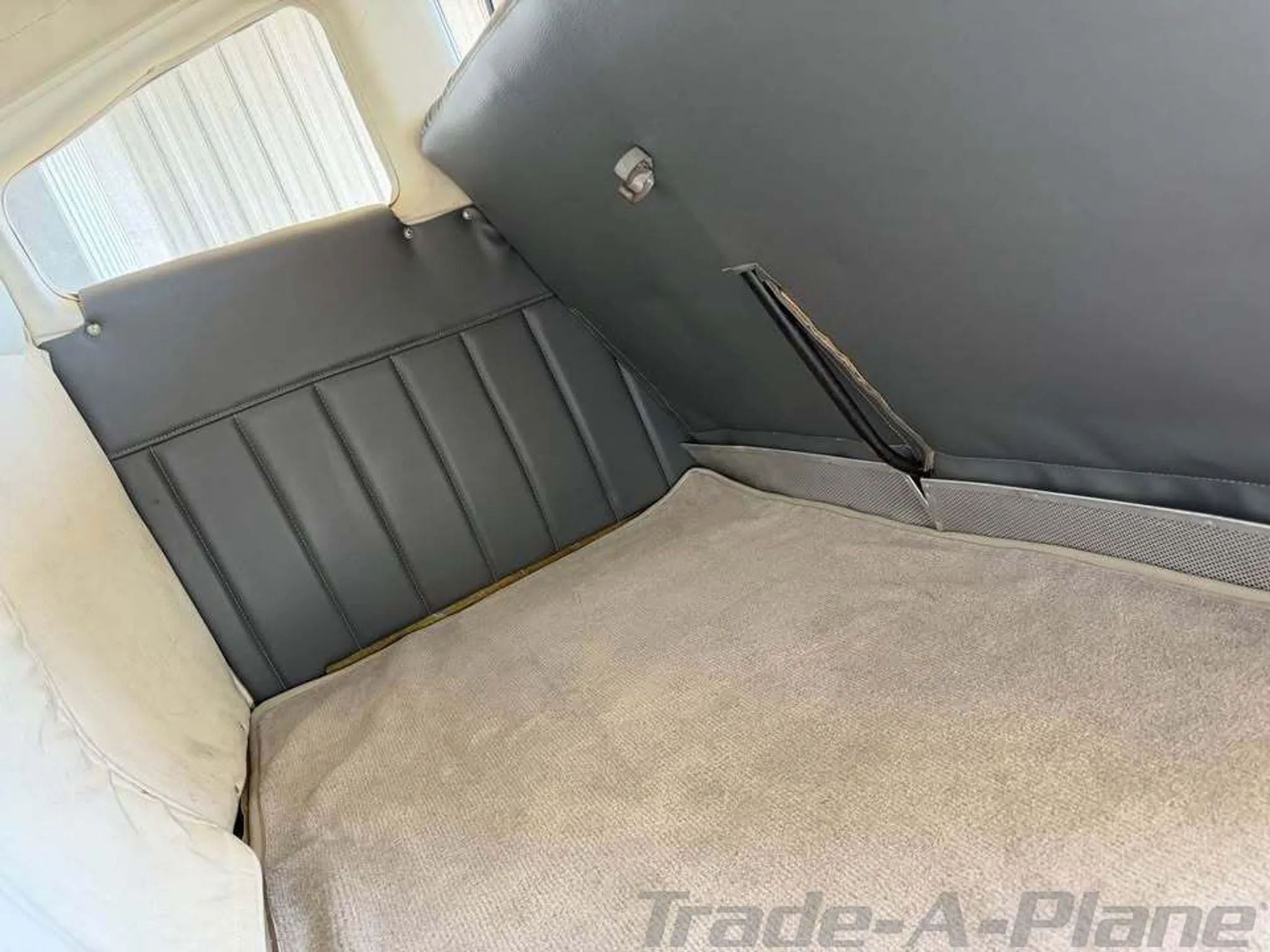 The rear cabin area of the aircraft, showing gray upholstered walls and a light-colored carpeted floor.