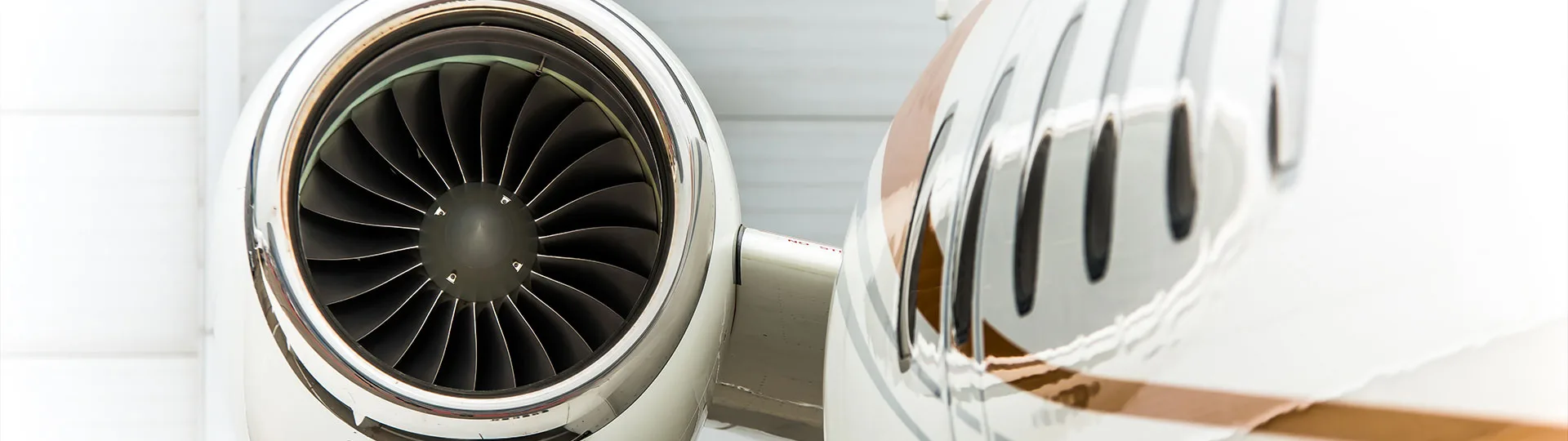 A close-up view of a jet engine intake and several passenger windows on a white aircraft.