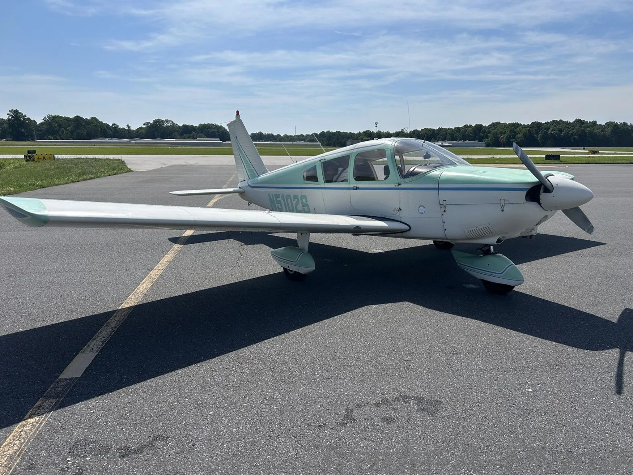 Another angle of the Piper Cherokee 180 parked on the runway.