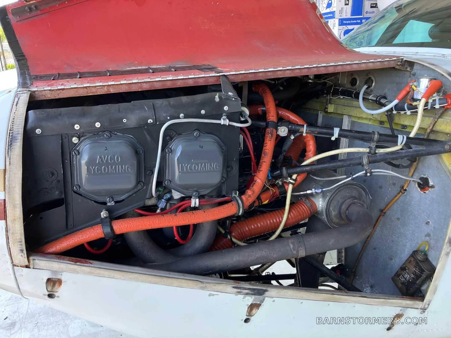 The open engine compartment of an aircraft, revealing the Lycoming engine with its cylinders and various hoses and components.