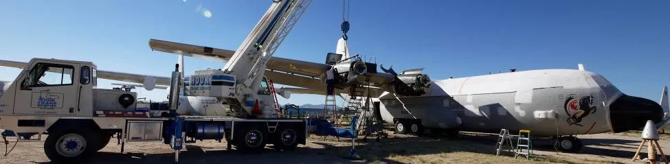 A C-130 Hercules being serviced with a crane.