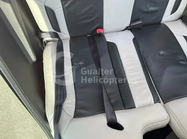 The rear passenger seats of an aircraft, upholstered in black and white leather with seatbelts.