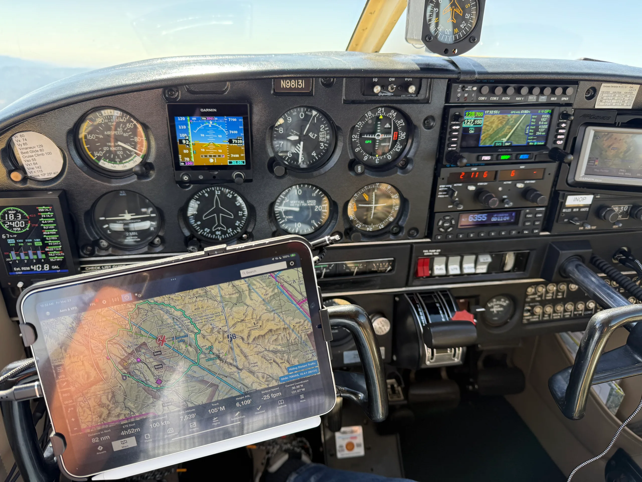The cockpit of an aircraft (N98131) showing the instrument panel with a tablet displaying a navigation map.