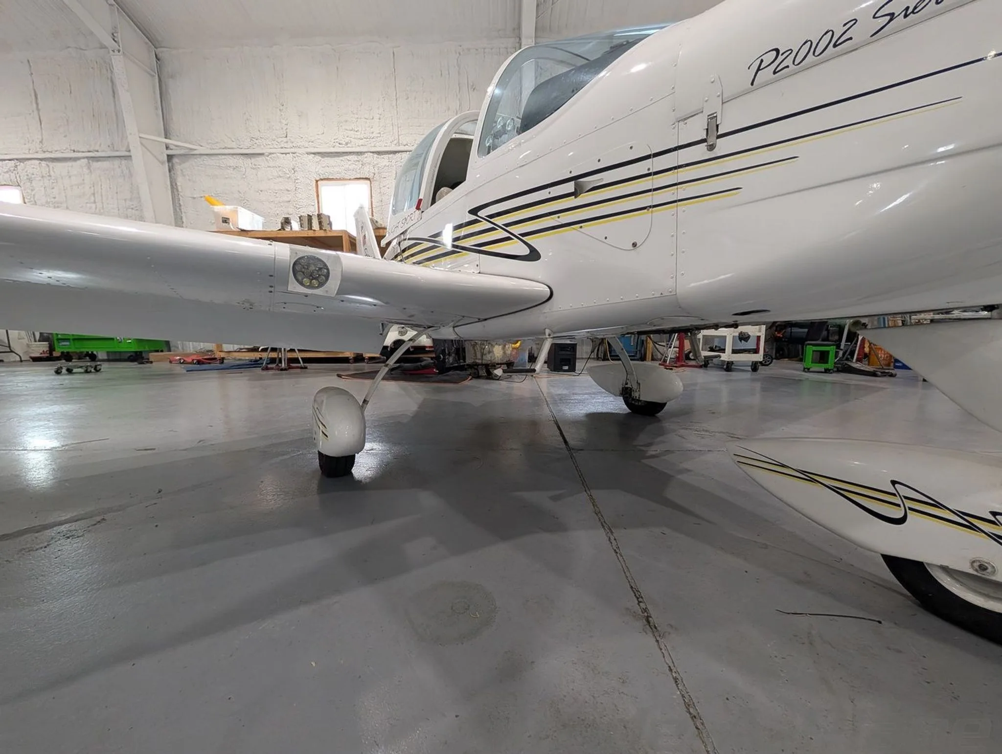 A close-up side view of the white Tecnam P2002 Sierra fuselage and main landing gear.
