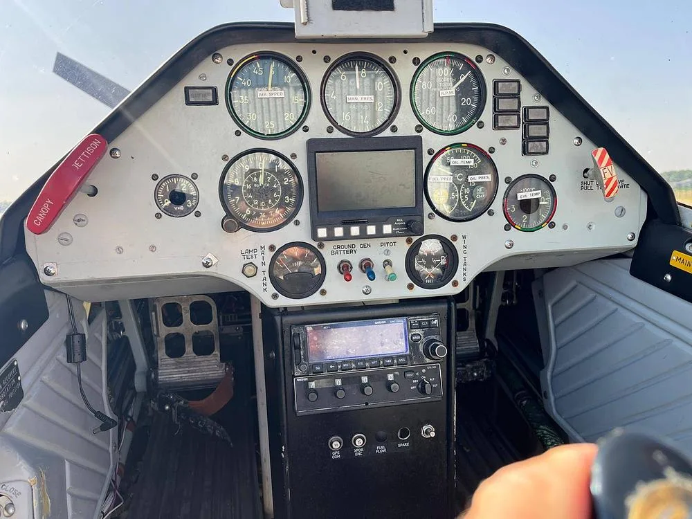The cockpit of an aircraft showing the instrument panel with various gauges, a display, and radio equipment.