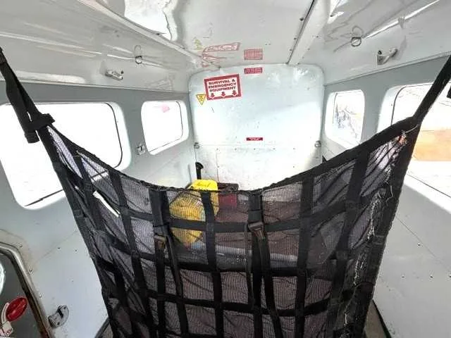 The interior cabin of an aircraft showing a large black cargo net hanging from the ceiling.