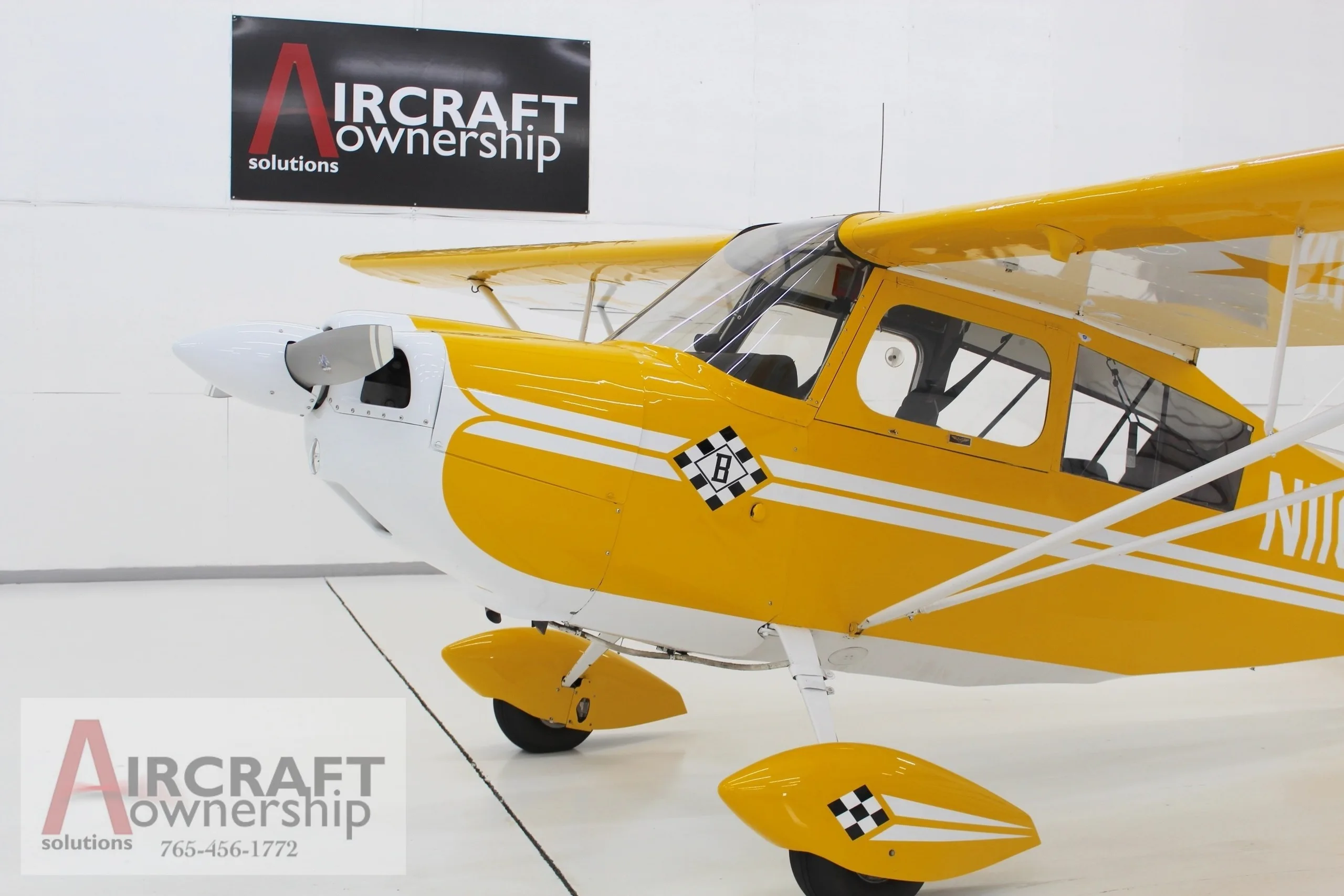 A close-up view of the front fuselage and propeller of the yellow and white N11646 aircraft in a hangar.