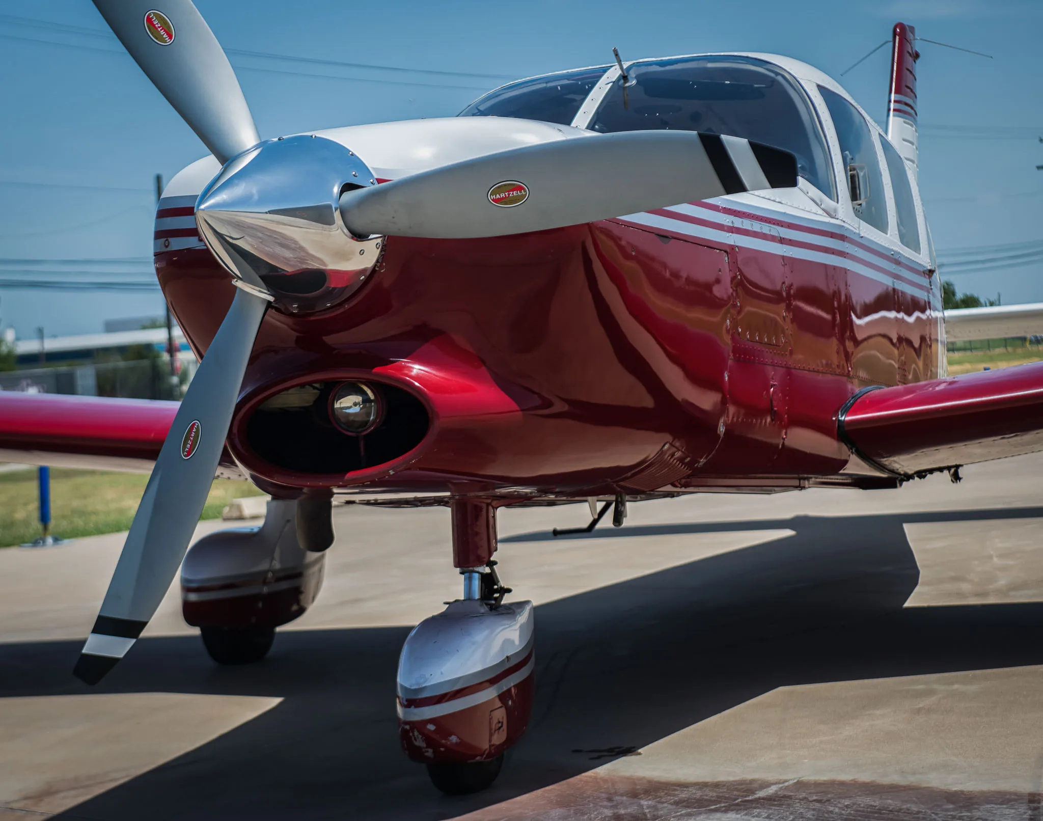 A close-up view of the propeller and nose section of a red and white aircraft.