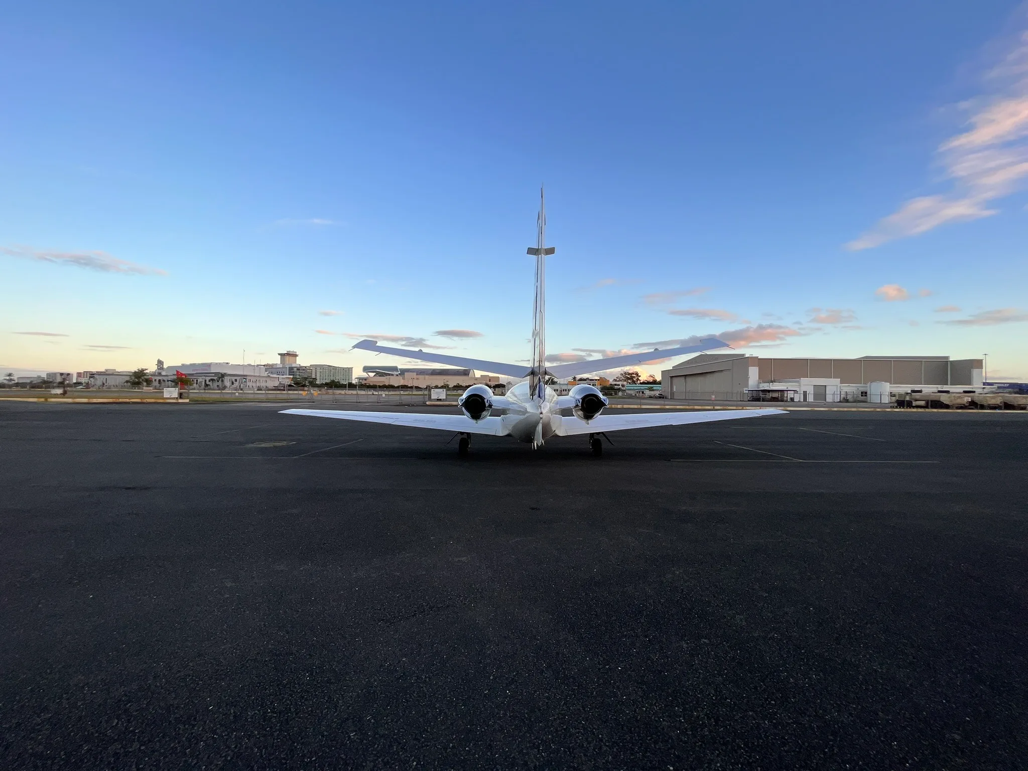 Rear view of a white Cessna Citation Mustang on the tarmac at sunset.