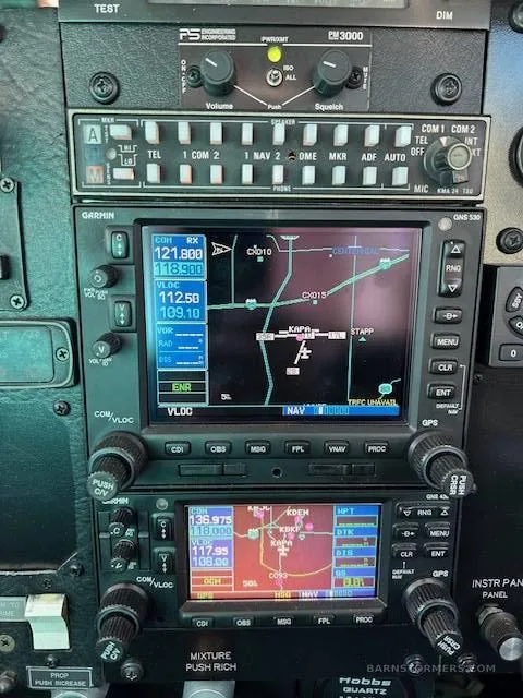 A close-up of the avionics stack in a Mooney M20J cockpit, featuring two Garmin GNS 530 GPS units displaying maps and flight information.