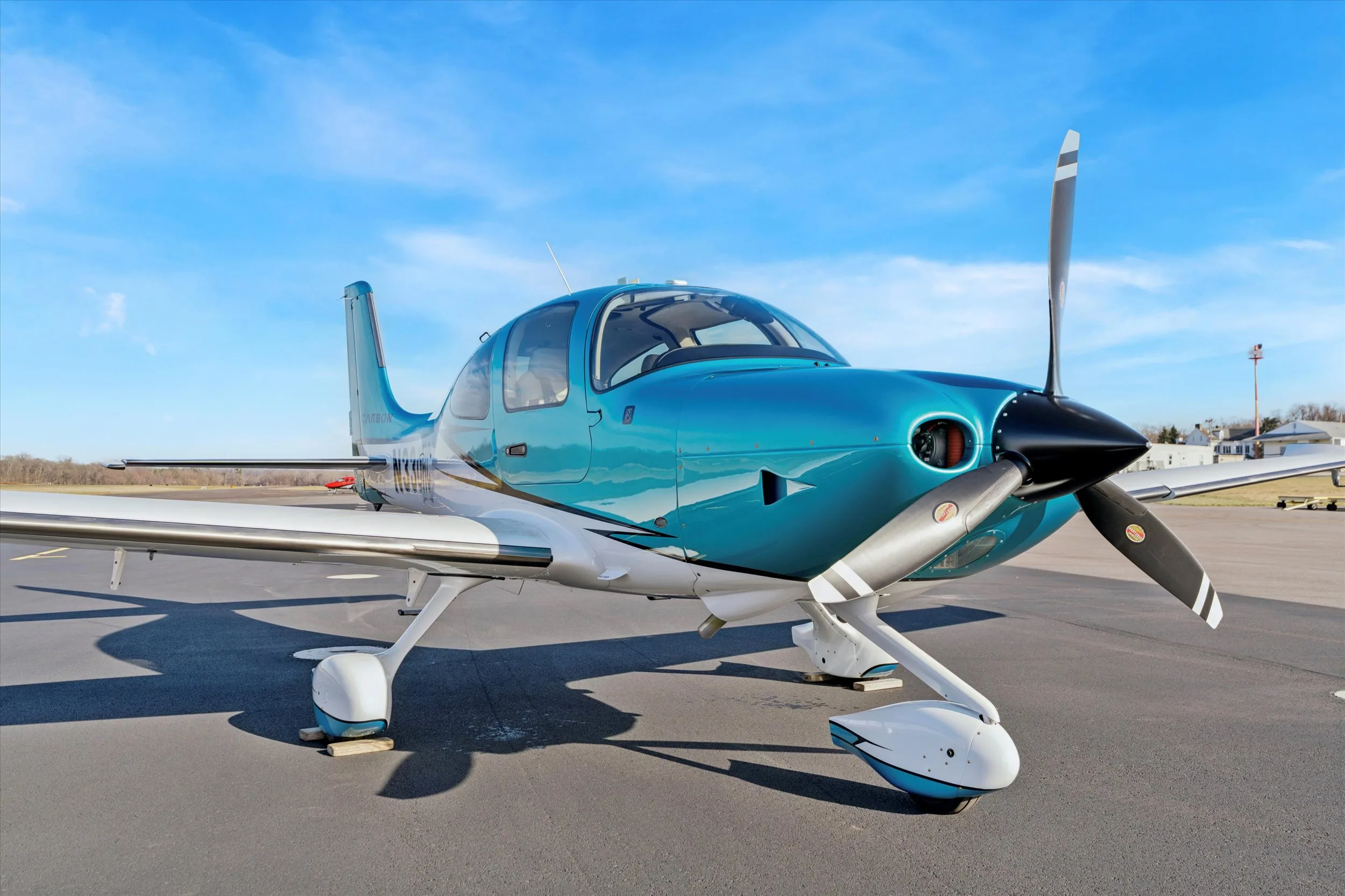 A close-up front view of the propeller and nose of a teal and white Cirrus SR22 aircraft, registration N330HC, on an airfield.