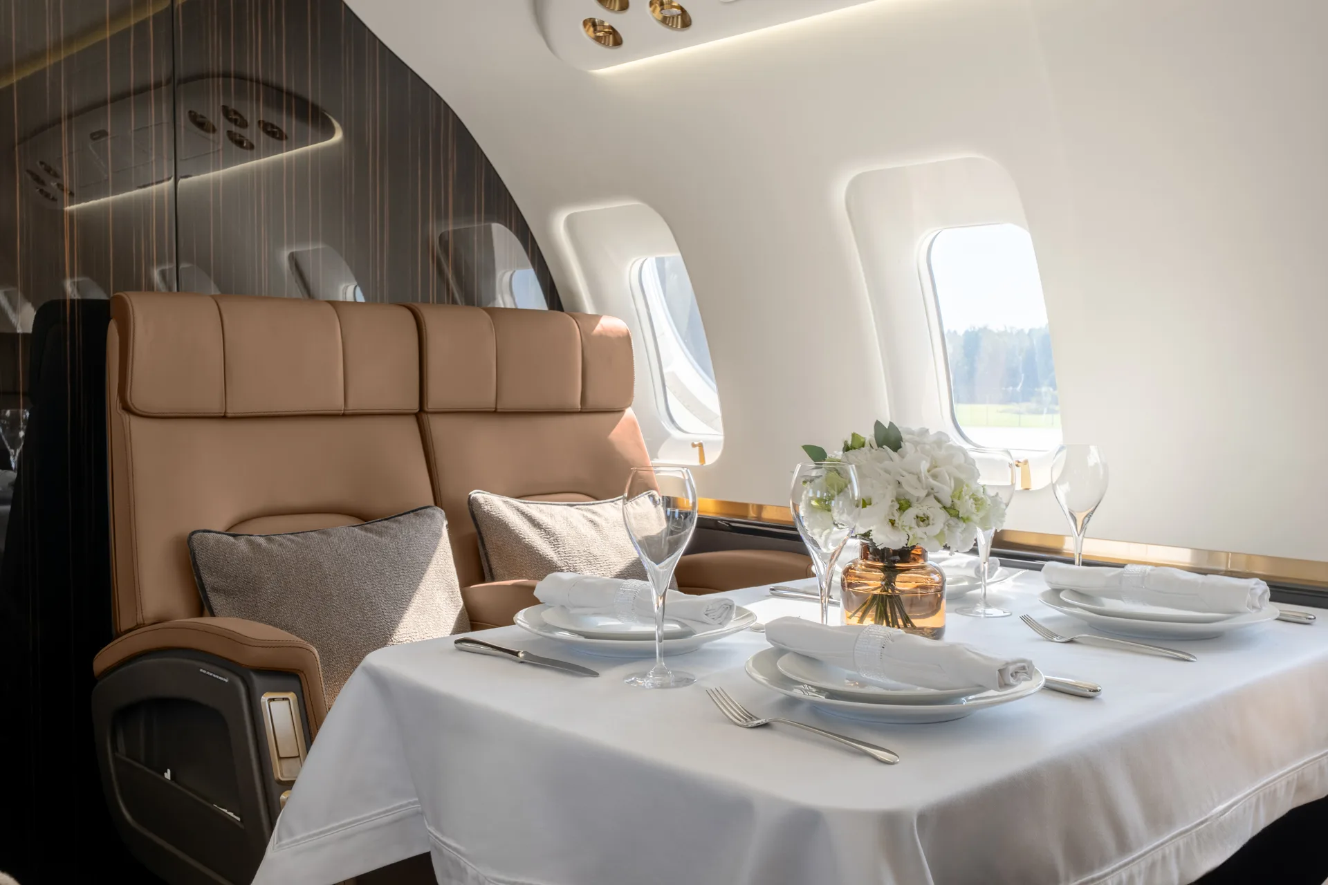 Another view of the aircraft's elegant dining table set with white dishes and a vase of white flowers.