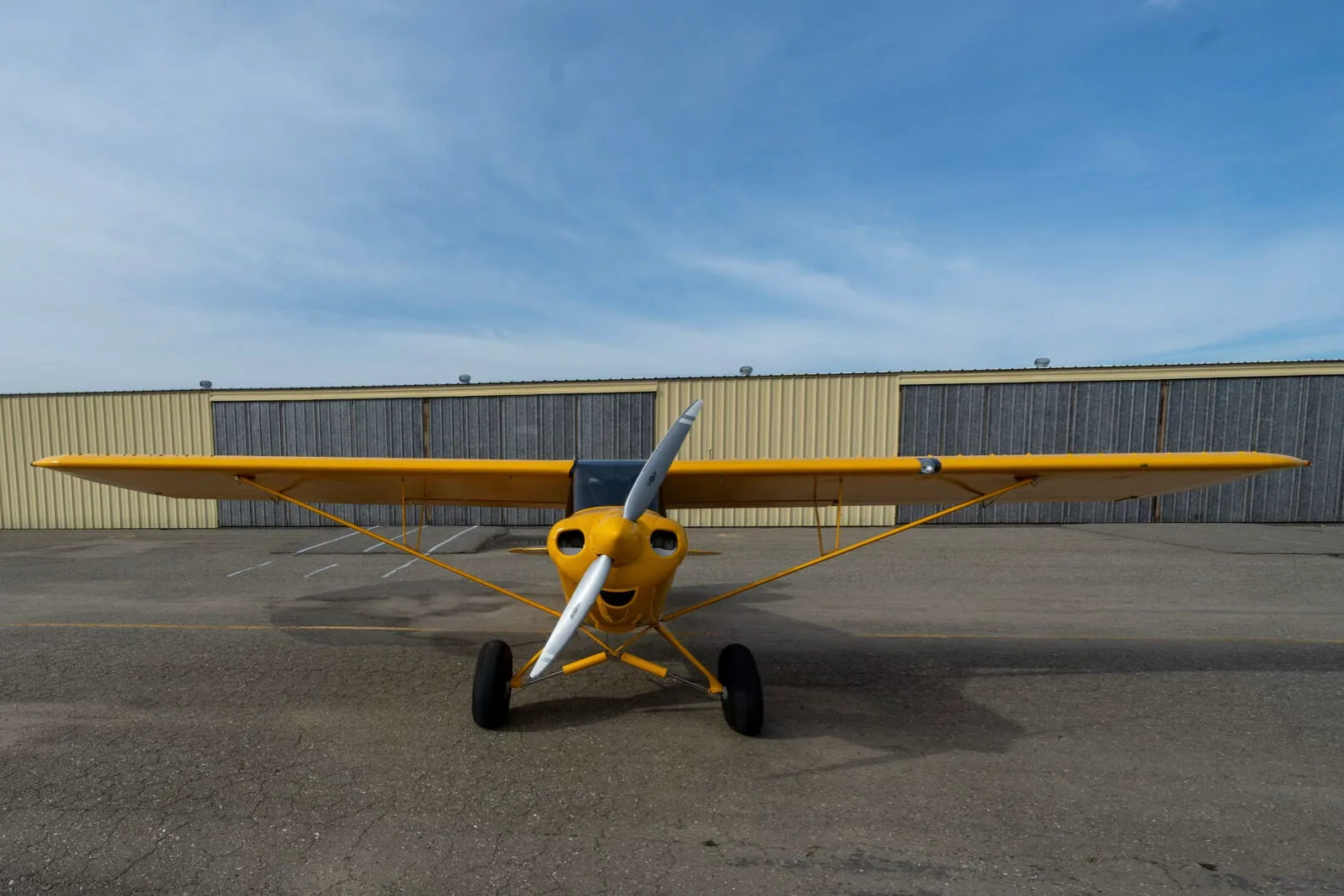A front view of the yellow CubCrafters Sport Cub S2 aircraft N579CC parked on an airfield.