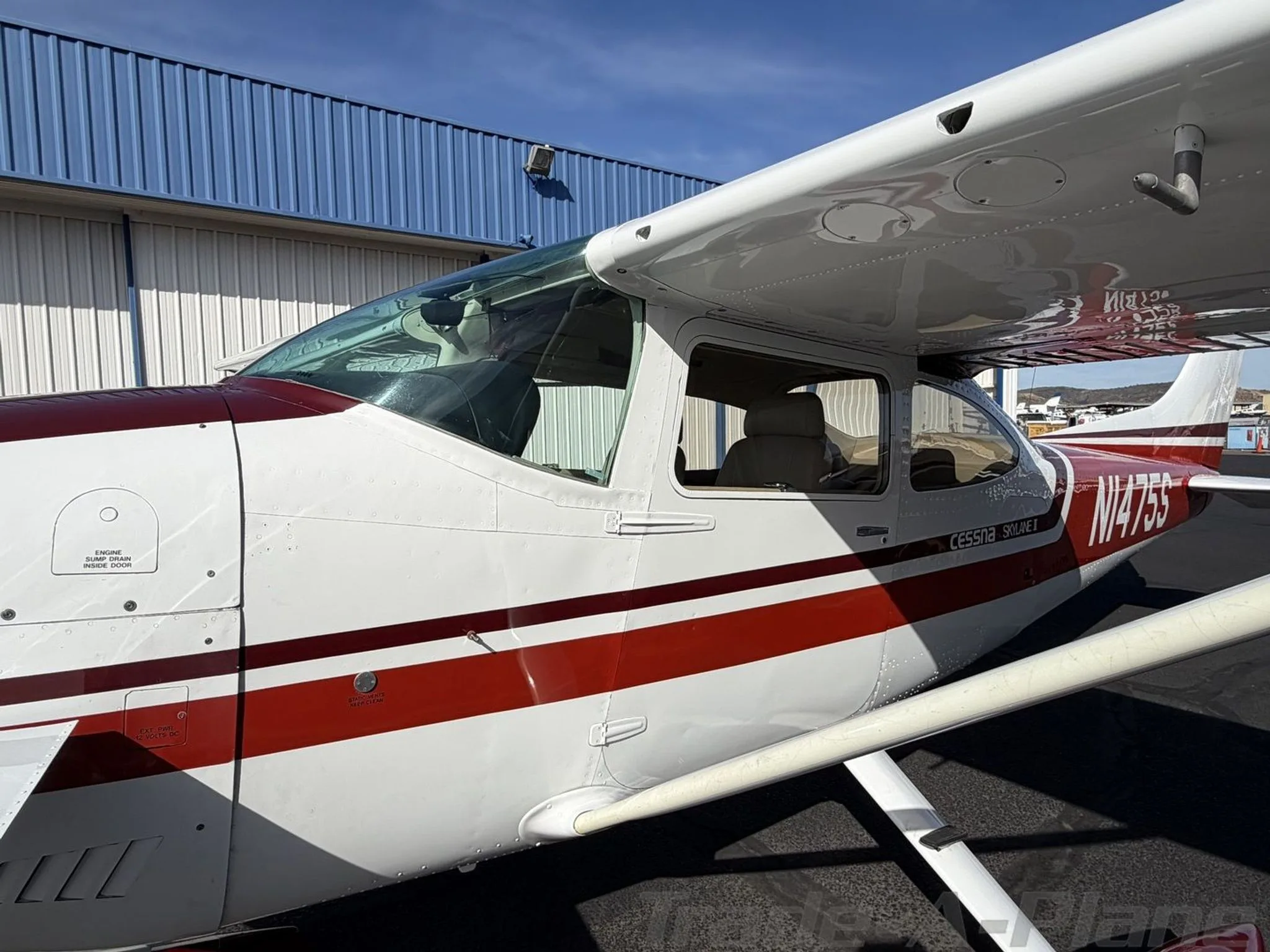 A close-up side view of the cockpit and front fuselage of the white and red Cessna Skylane II (N1475S).