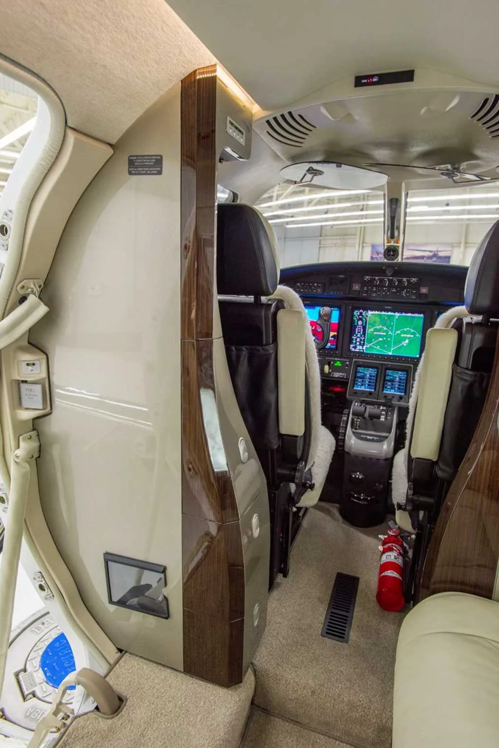 A view from the private jet's cabin looking forward into the cockpit, showing part of the instrument panel and pilot seats.
